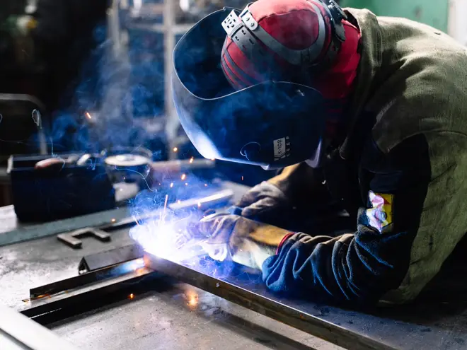 Welder laying a weld bead on steel in a fabrication shop